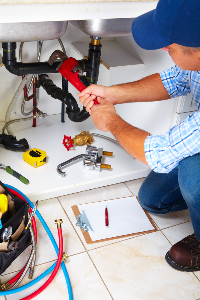 Plumber with Plumbing tools on the kitchen. Renovation.