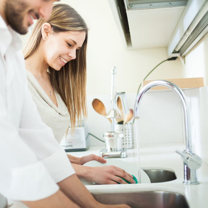 Young couple doing dishes Young couple doing dishes in the kitchen